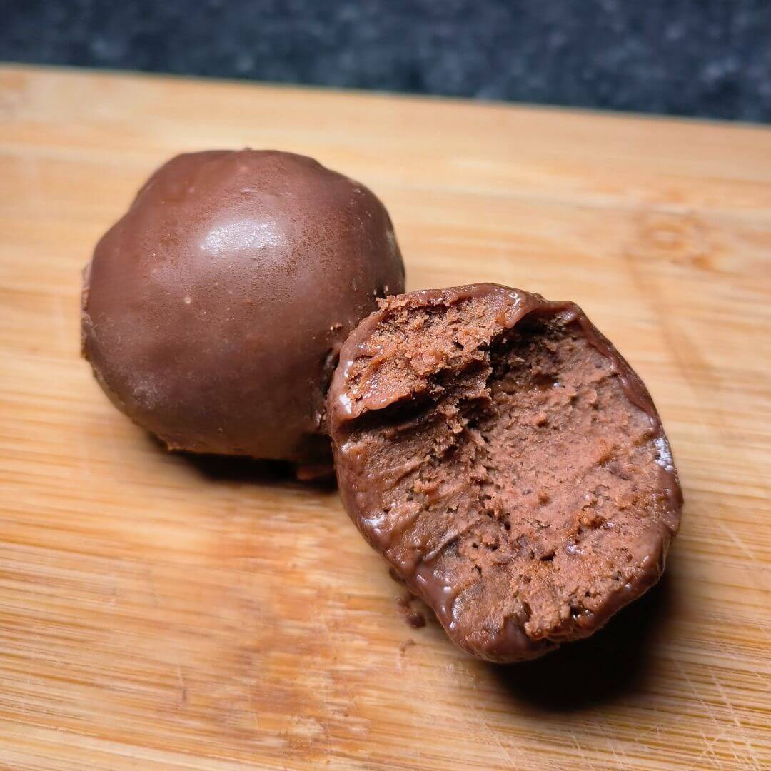 Chocolate protein brownie ball from Cloud 9 Meal Plans on a wooden board