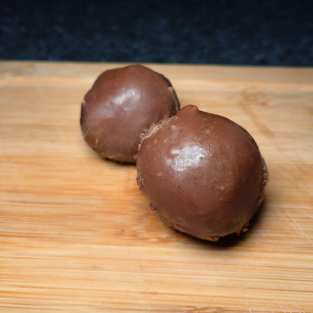Chocolate protein brownie ball from Cloud 9 Meal Plans on a wooden board.