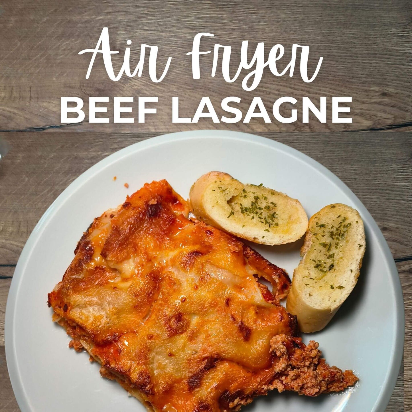 A dish of Air Fryer Beef Lasagne with a side of bread and a sprig of parsley, on a plate with the text 'AIR FRYER BEEF LASAGNE' above.