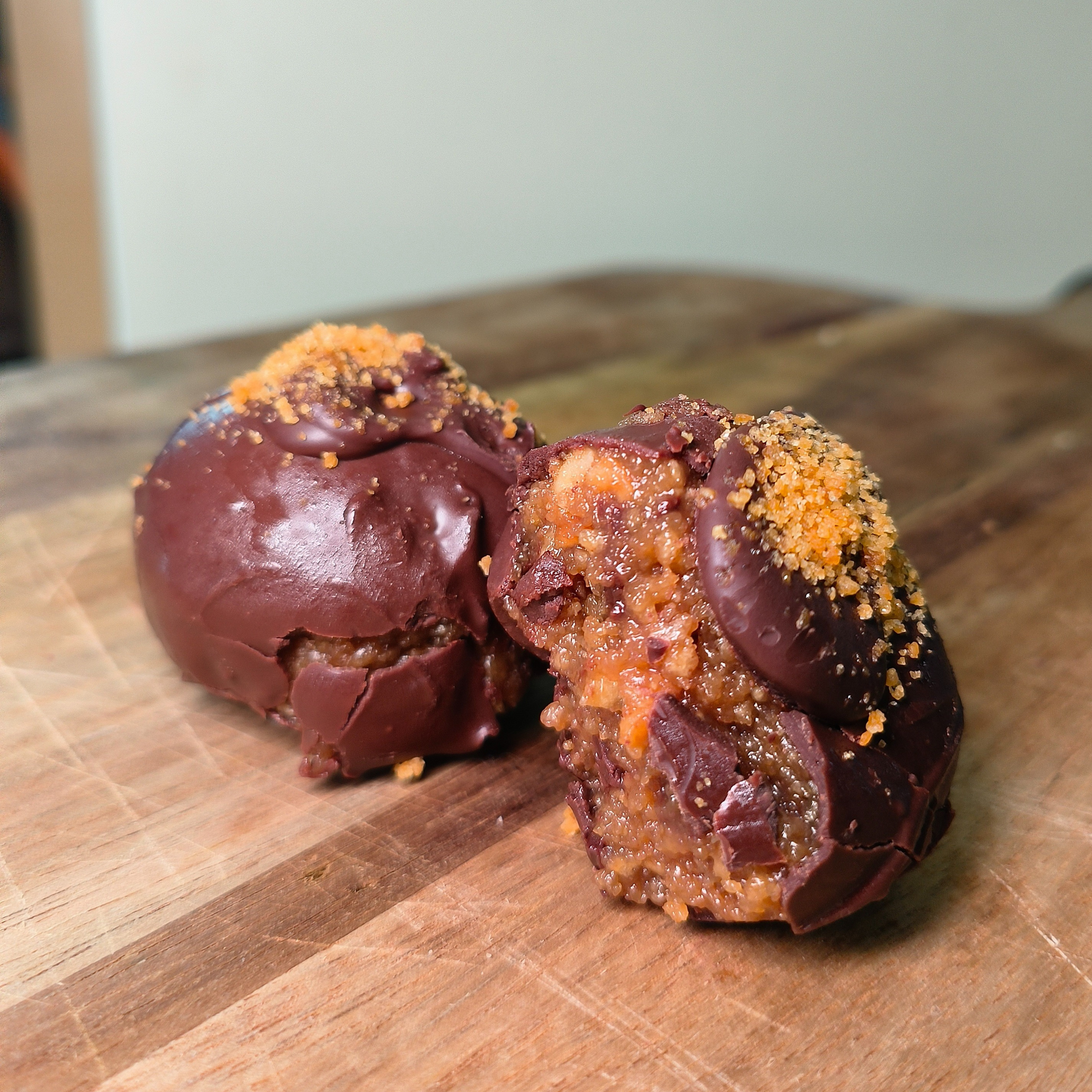 Chocolate truffles with a crumbly topping on a wooden surface